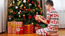 Dečak otvara poklone ispod jelke