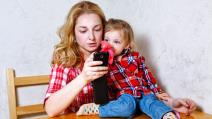 Majka pored deteta gleda u telefon