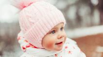 Dete u zimskom odelu sa roze kapom