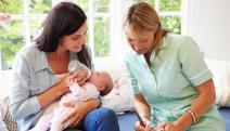 Patronažna sestra pored mame koja hrani bebu