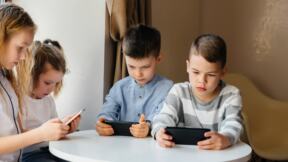 Deca sede za malim stolom i gledaju u telefone