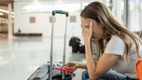 Umorna žena sedi pored prtljaga na aerodromu