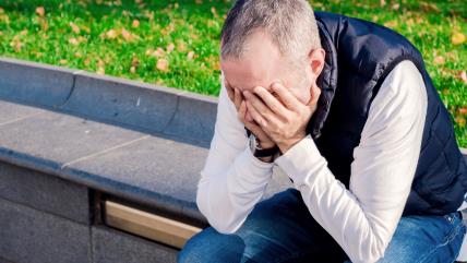 Zabrinut muškarac sedi na klupi napolju