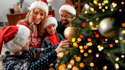 Roditelji sa decom ukrašavaju novogodišnju jelku