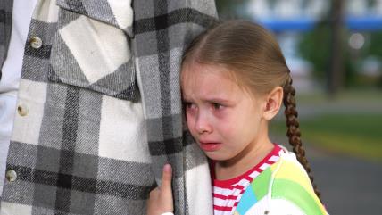 Uplakana devojčica se krije pored roditelja