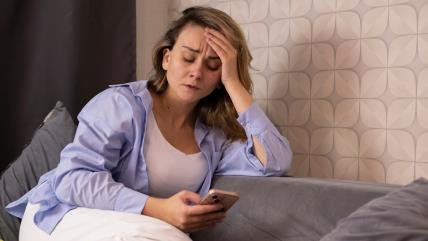 Tužna žena čita poruku na telefonu