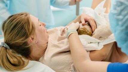 Žena drži bebu nakon poroođaja