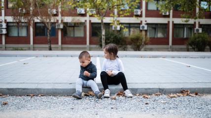 Dečak i devojčica sede na pločniku