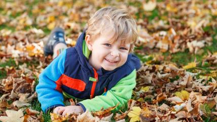 Dečak leži na travi i lišću