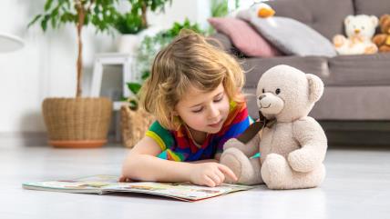 Dete čita knjigu sa plišanim medom