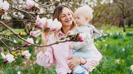 Mama sa bebom pored cveta na drvetu