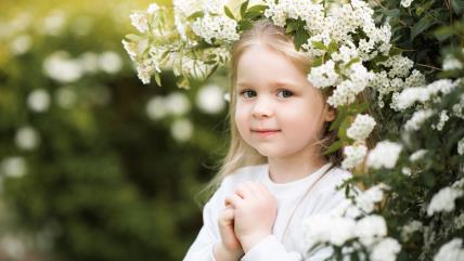 Devojčica stoji pod procvetalim drvetom