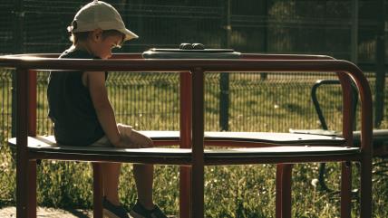 Dečak sam sedi u parku