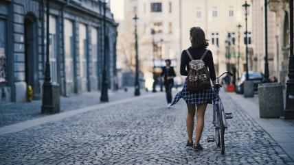 Žena gura bicikl na ulici
