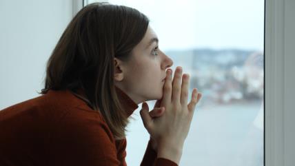 Tužna devojka sedi pored prozora