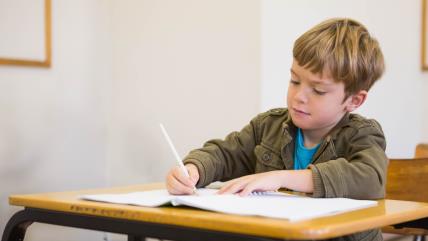 Dečak piše u školskoj klupi