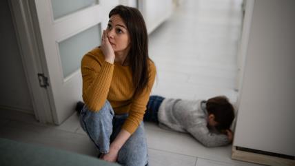 Mama pored deteta koje ljuto leži na podu