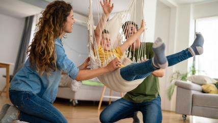 Roditelji se zabavljaju sa detetom u ljuljašci kod kuće