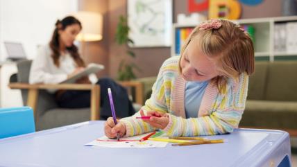 Devojčica crta sa dečjim psihologom iza