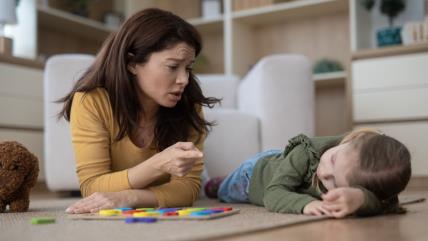 Mama grdi dete koje ljutito leži na podu