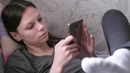 Žena leži i gleda u telefon