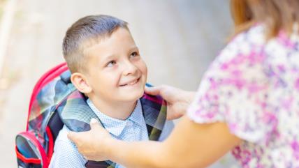 Mama namešta ranac sinu za školu