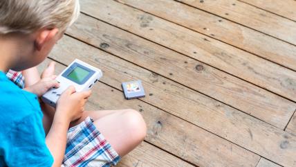 Dečak sedi i igra Gejmboj