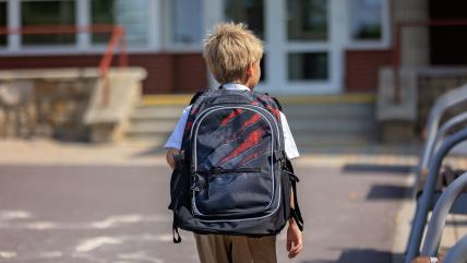 Dečak sa rancem ispred škole