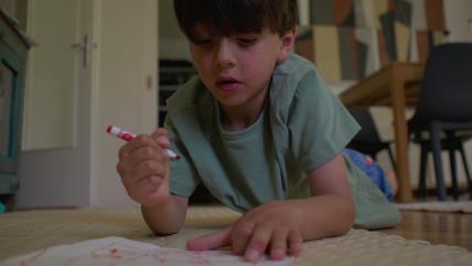 Dečak leži na podu i crta