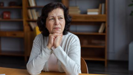 Usamljena starija žena sedi za stolom