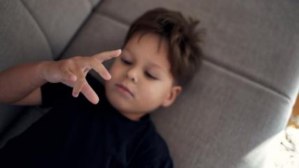 Dečak upliće prste dok leži na kauču