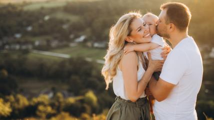 Mama i tata grle i ljube bebu u prirodi