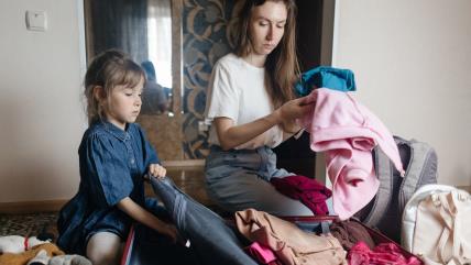 Mama sa ćerkom pakuje stvari u kofer