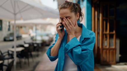 Žena nervozno priča na telefon na ulici