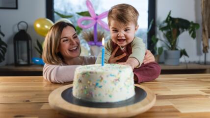Mama sa detetom pored torte za prvi rođendan