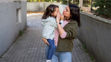Mama nosi ćerku i briše joj oko