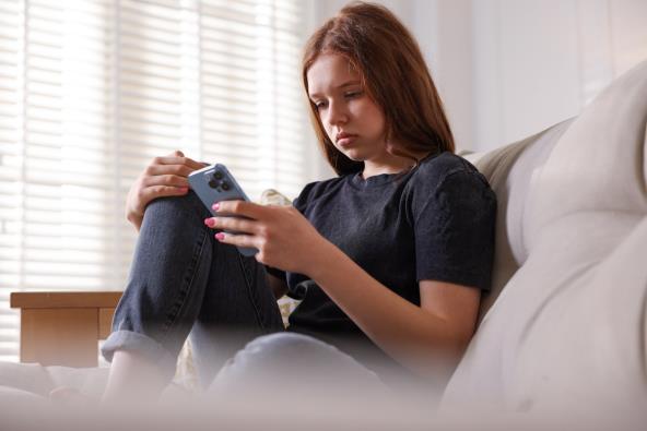 Tužna tinejdžerka drži mobilni telefon