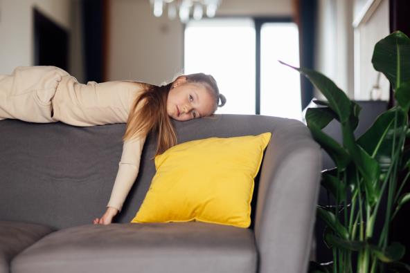 Devojčica leži na naslonu kauča