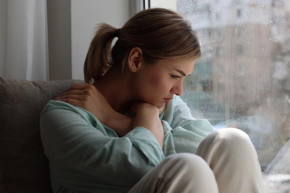 Tužna žena sedi pored prozora