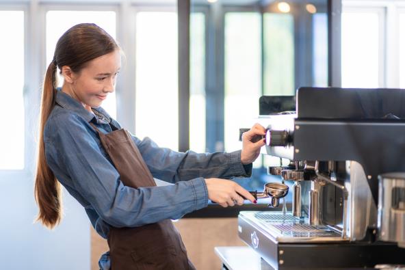 Mlada devojka priprema kafu u kafiću