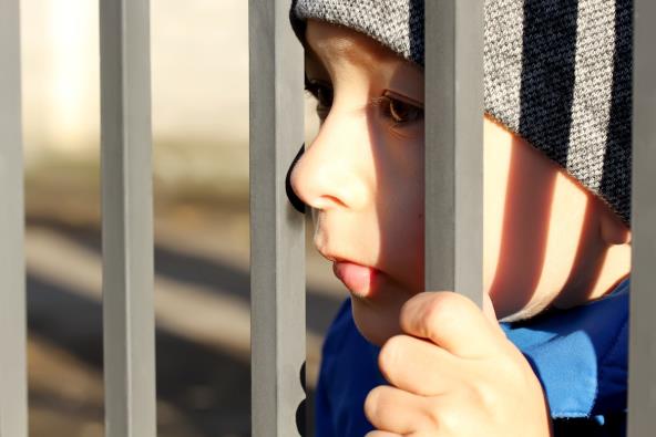 Dečak gleda kroz rešetke ograde