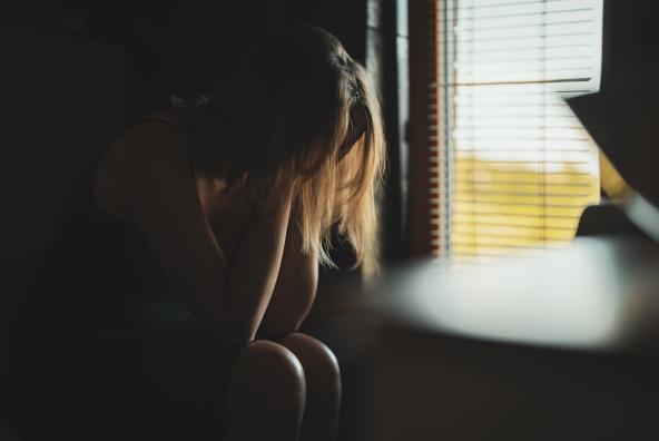 Uznemirena žena sedi pored prozora