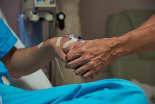 Žena drži ruku muškarca u bolničkom krevet