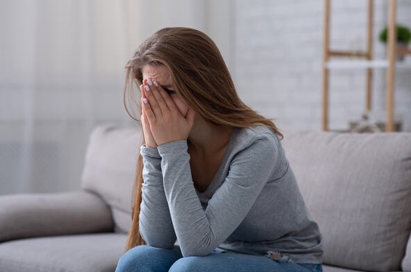 Žena plače i drži ruke preko lica