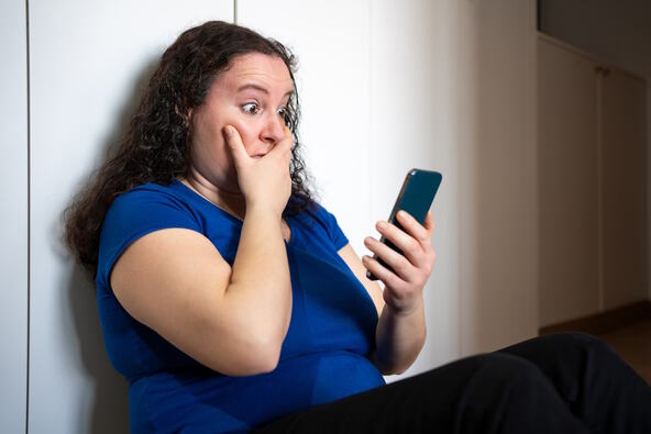 Začuđena žena gleda u telefon